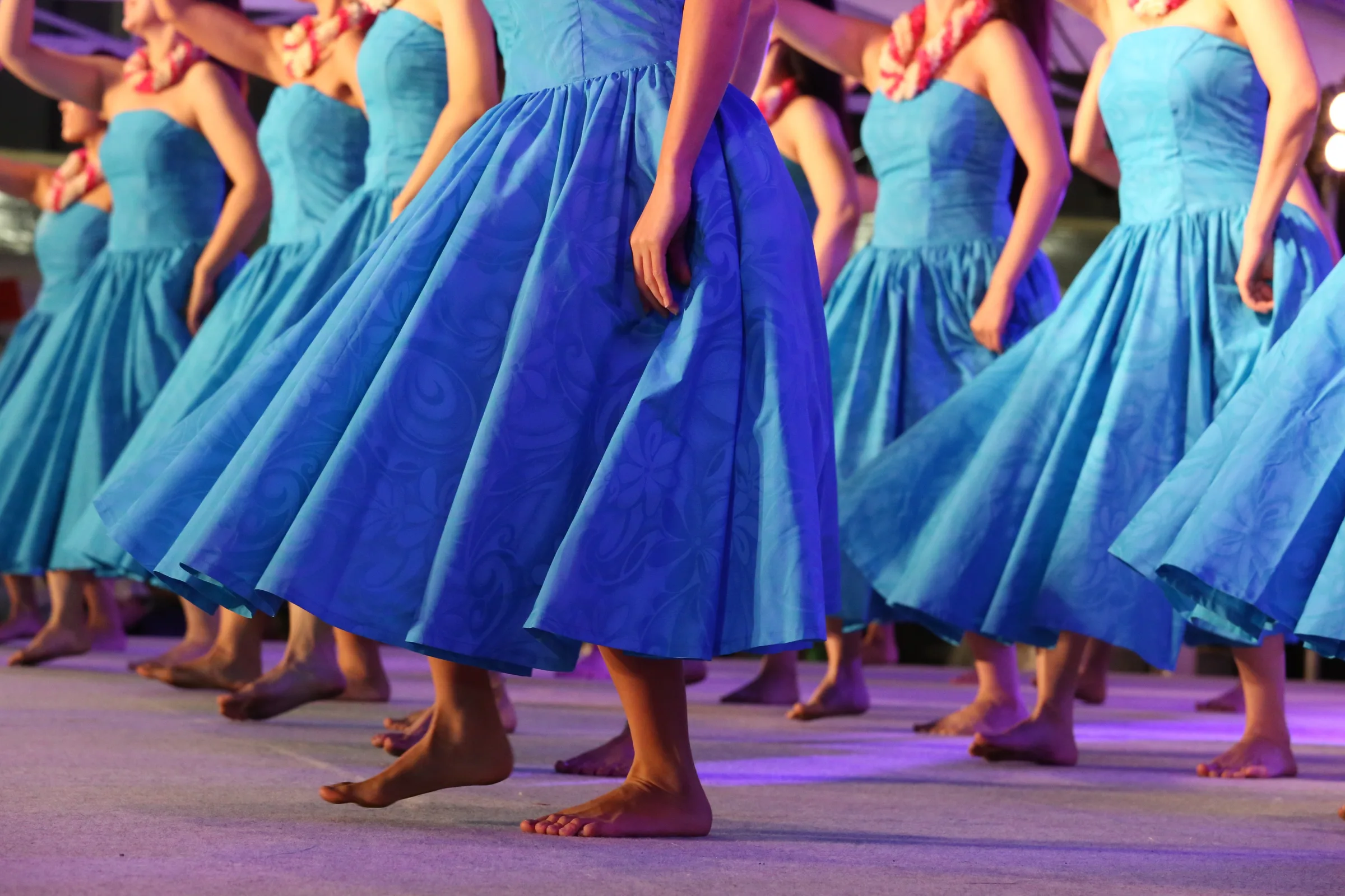 Row of dancers in blue dresses performing barefoot on a stage