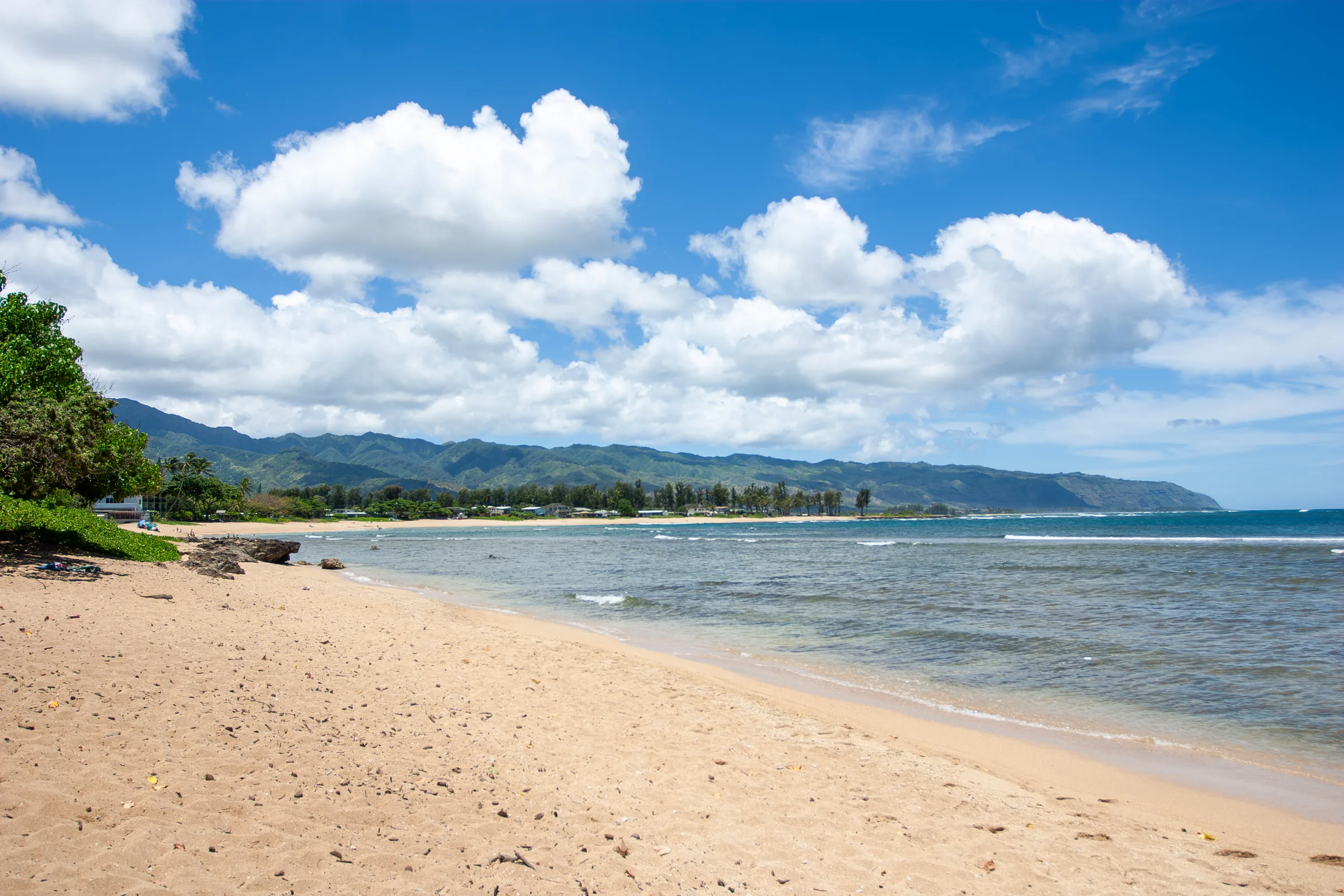 Sandy beach curving toward green mountains along a calm bay